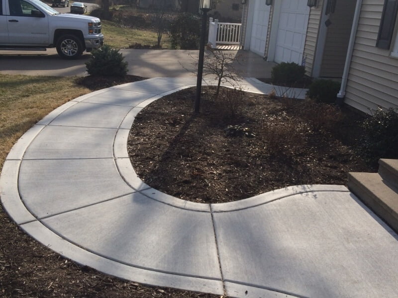 Concrete sidewalk of a house in a round shape connecting driveway with entrance.
