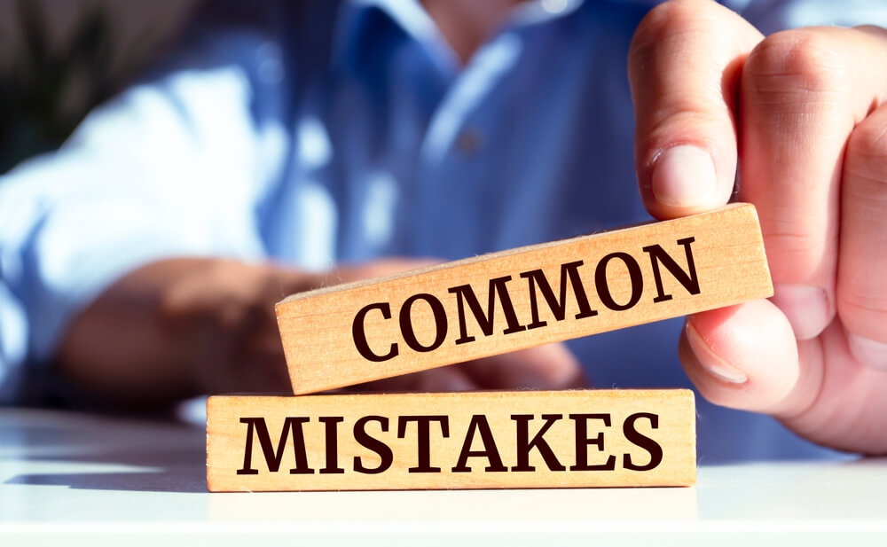 Guy holding 2 little wooden sticks that have "common mistakes" scared on them.
