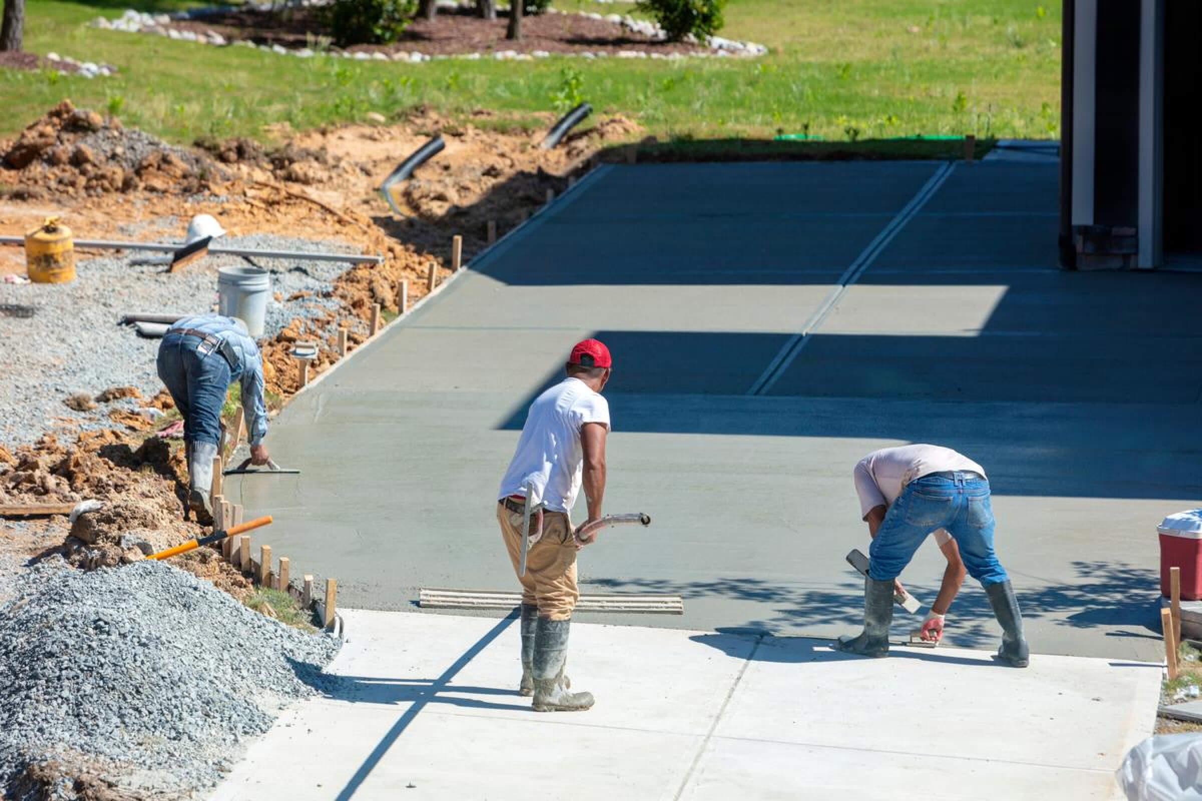 Three concrete workers working on making a concrete driveway.