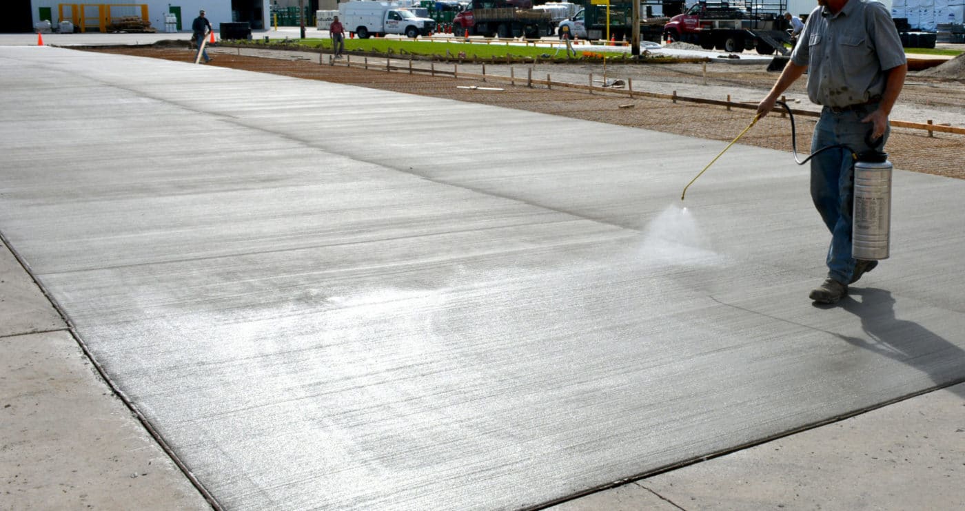 Concrete contractor curing concrete with water.