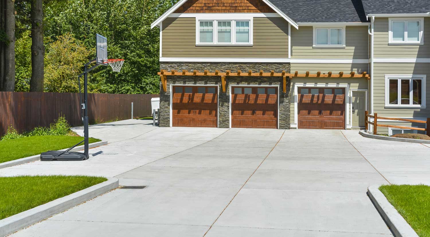 Beautiful spacious concrete driveway leading to big house with 3 garage doors.